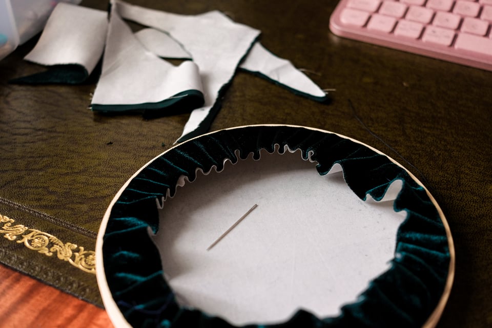 A photo of the embroidery hoop with the fabric pulled tight around the back, and trimmed, resulting in a neat flat circle