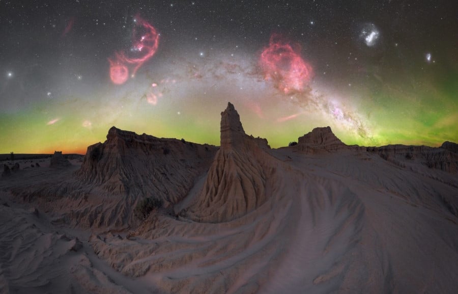 The brilliant star-studded Milky Way above a desert landscape with hoodoos and sand.
