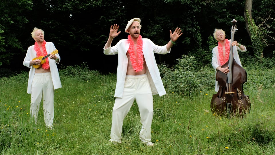 An uncertain Simon waves his hands in dance, flanked by a ukulele playing Simon, and a double bass playing Simon
