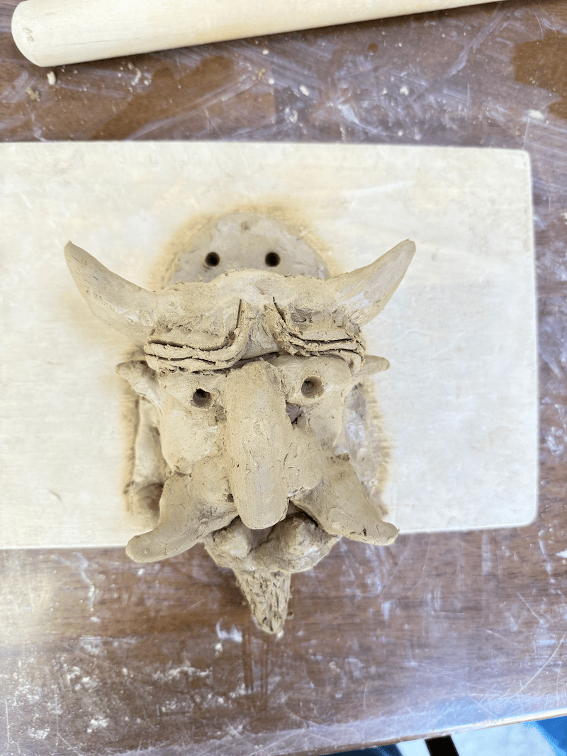 a clay sculpture of an evil repelling demon head, not yet fired. this is the one Terri made.