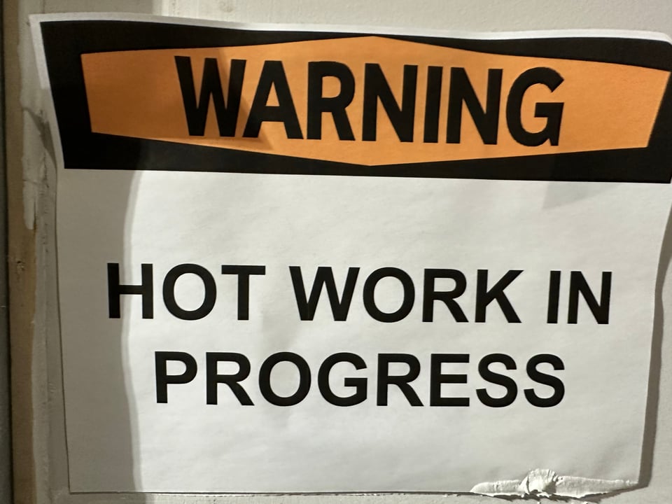 paper sign reading WARNING HOT WORK IN PROGRESS