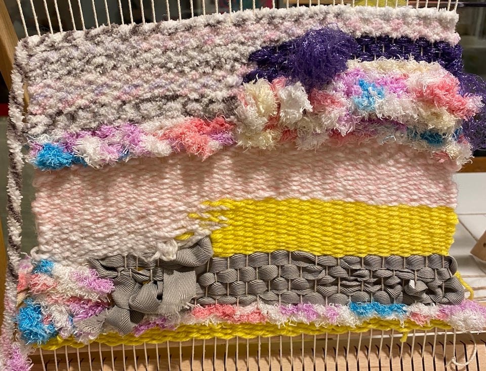 a loom with pastel yarn on it in an abstract random orientation