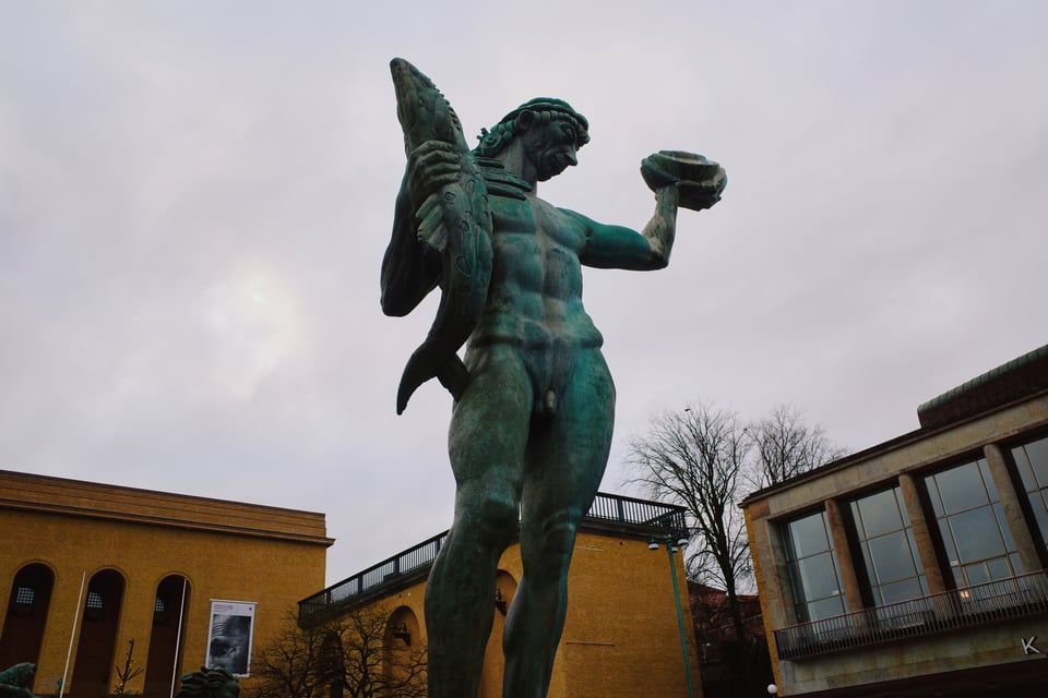 A statue of Poseidon holding a fish and a shell.