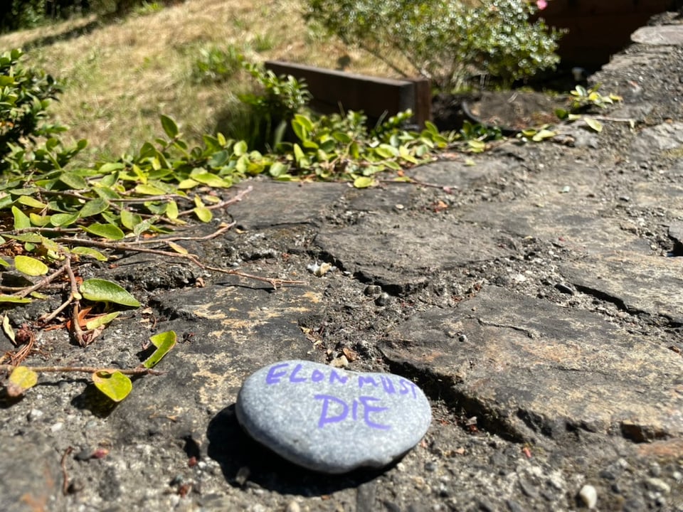 a heart-shaped stone sitting on top of the stone wall in the Morcom Rose Garden; in pink paint pen the stone reads, "Elon must die"