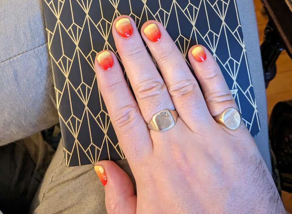 A hand with nails painted in yellow that turns into dark orange.