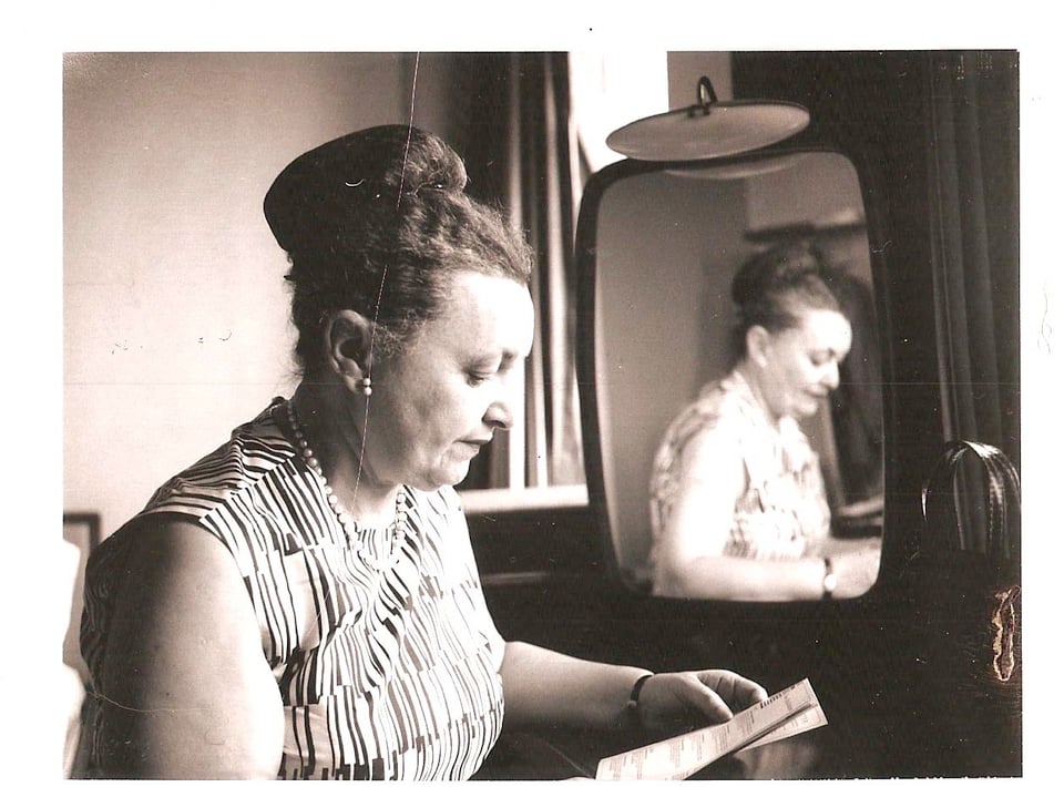 Woman with a topknot bun reading a pamphlet next to her mirrored reflection