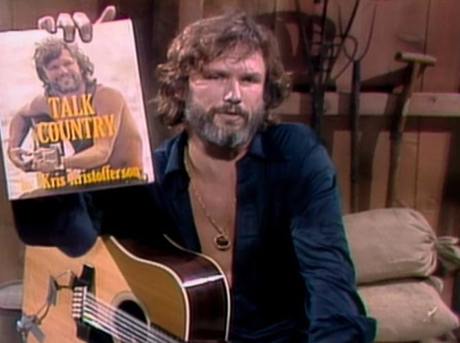 a man holding an acoustic guitar and a book