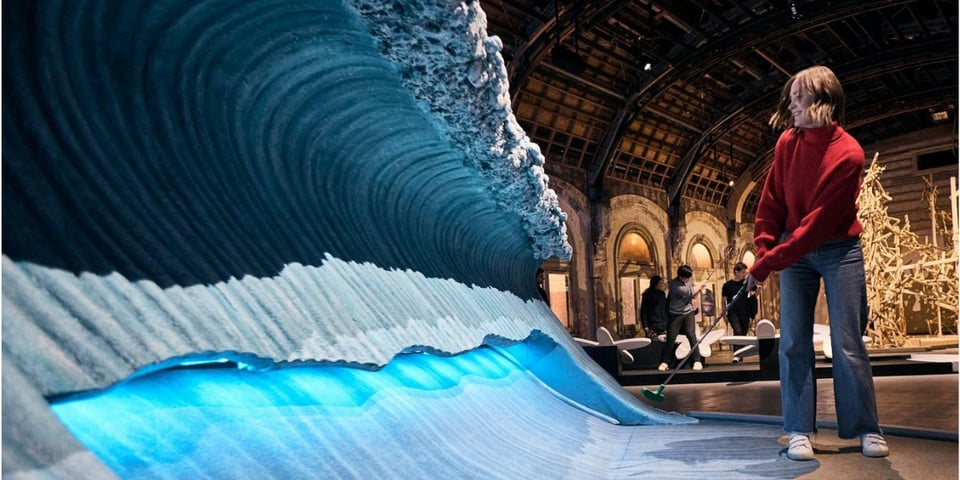 A woman playing mini-golf across a sculpture of a wave.