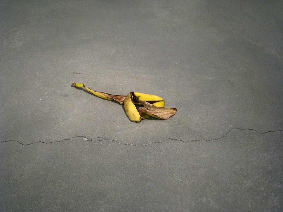 A color photograph shows a banana peel tossed on a cement floor