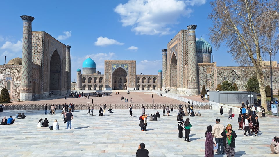 People walking in front of a the Registan Complex in Uzbekistan