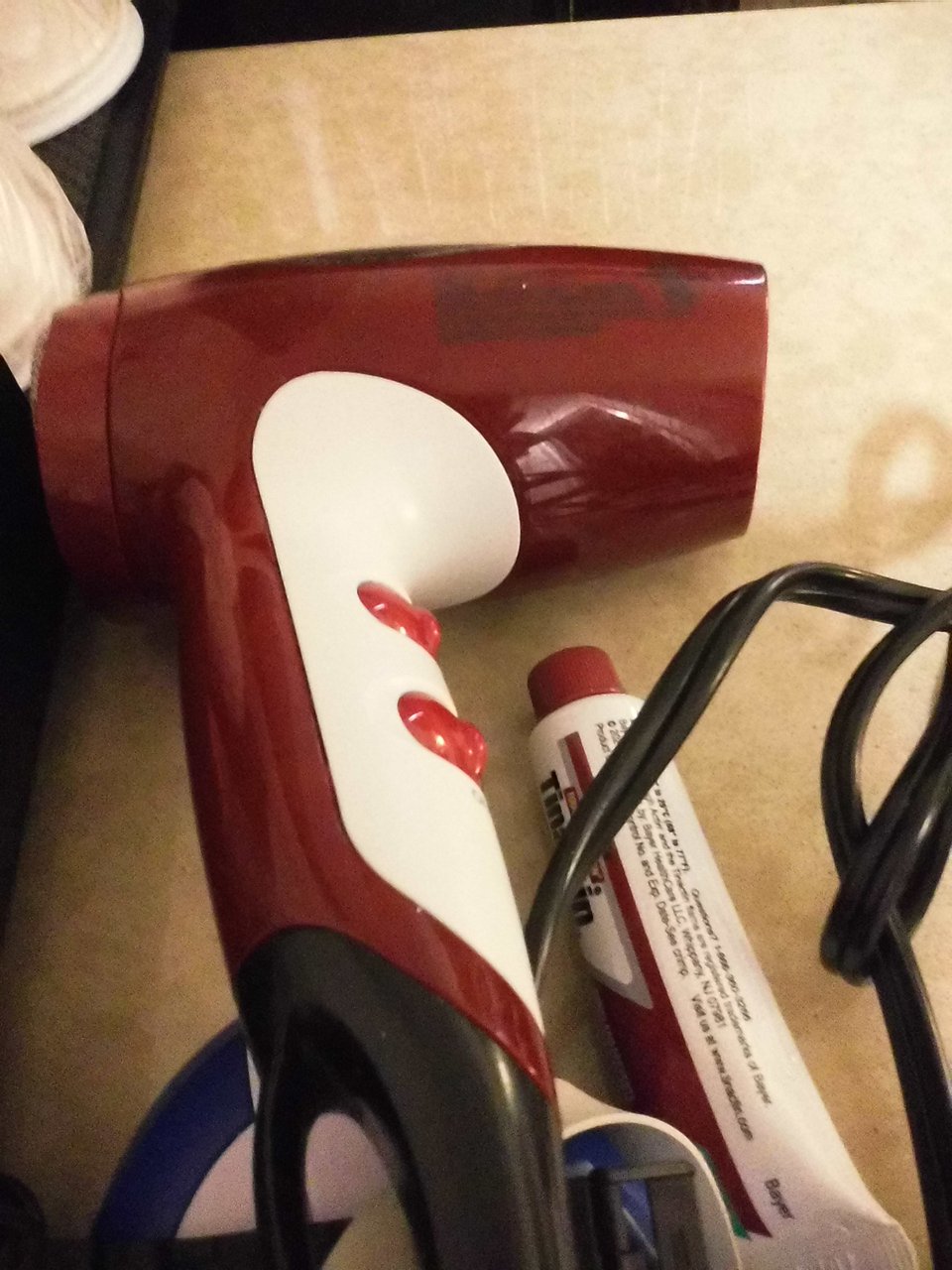 digital Instax photo of a hair dryer and a tube of tin actin on a hotel room counter