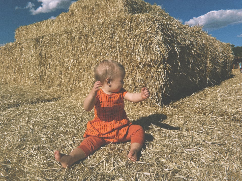 a baby sitting in front of hay bales