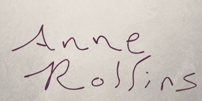 Off white background. Dark purple-pink handwriting reads "Anne Rollins."