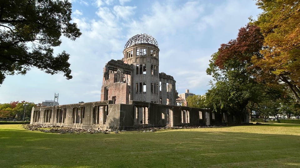Photograph of a ruined building, at the centre of which is a circular tower topped by the steel lattice that once supported a rood dome.