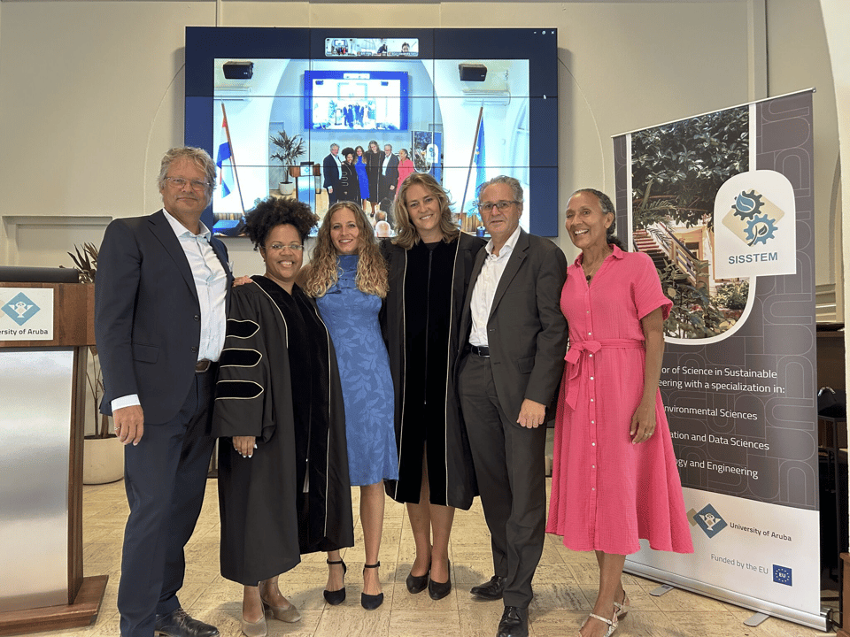 Dr. Amber van Veghel after her PhD defense, sharing a picture with her co-promotors and parents in front of the Aula at the University of Aruba.