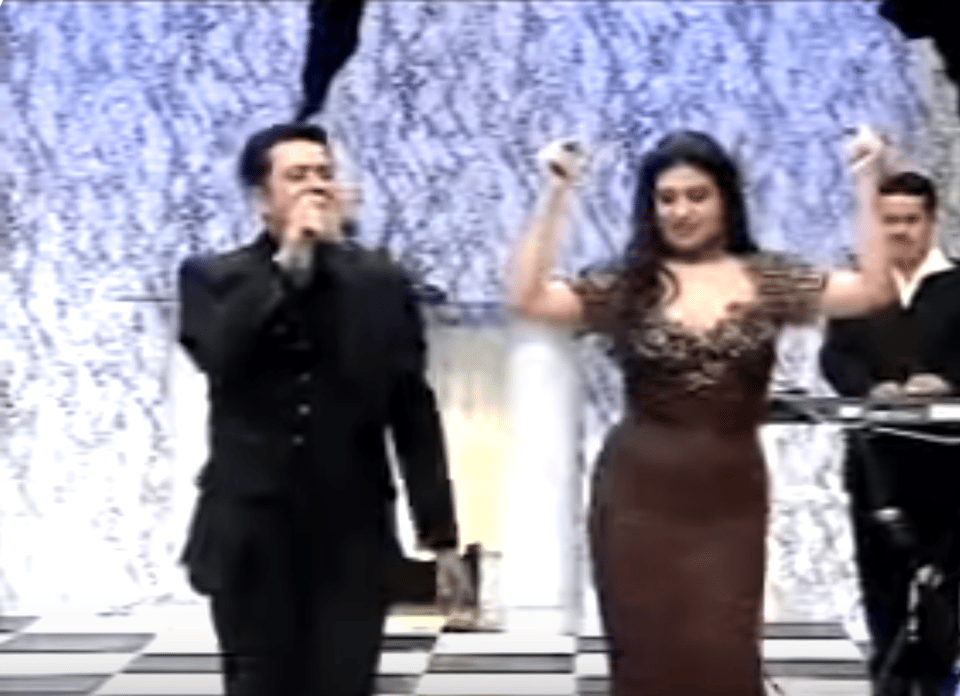 A singer sings as Fif Abdo dances in a brown dress