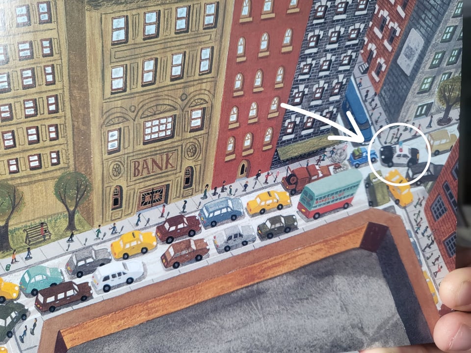 close-up of Illustration from the book that shows an aerial view of a city street. The cop car is circled with an arrow pointing to it to show how it's causing the traffic jam