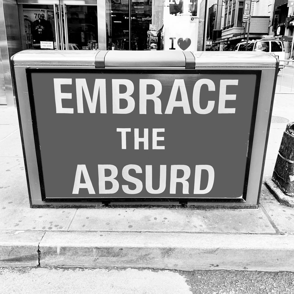 Billboard in New York City behind trashcans saying "Embrace the Absurd"
