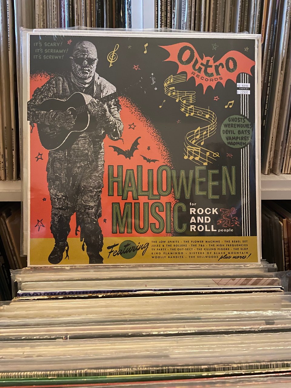 A vinyl album on a stack of other vinyl albums. The cover features a picture of a mummy playing guitar and the words HALLOWEEN MUSIC