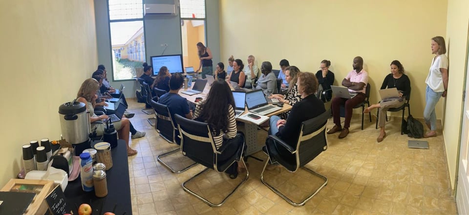 A room full of people sitting behind their laptops, following along with the instructor in front that is using a larger screen.
