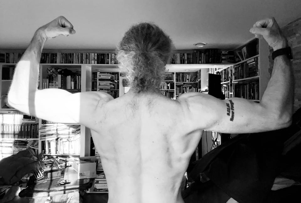 photo of shirtless man flexing, from behind from the waist up