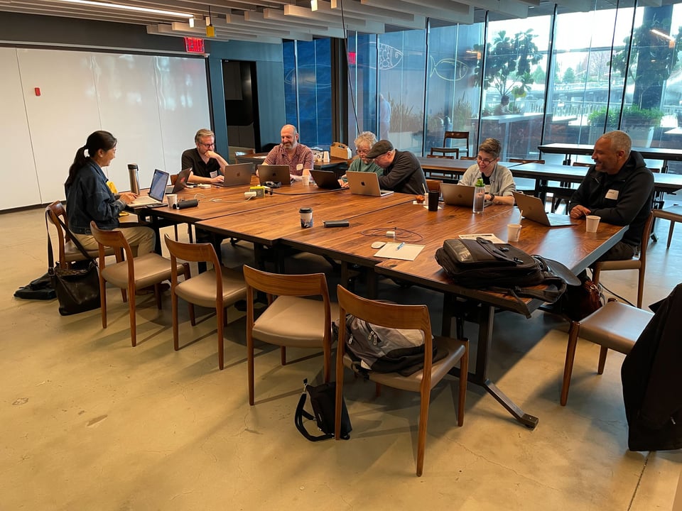 A diverse group of people with laptops around a table at Pier 57