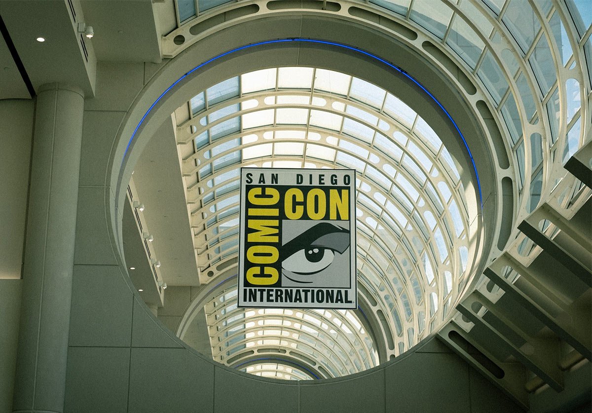 A photograph of the San Diego Comic Con logo hanging in a circular window. The logo is of a eye with a hard stare.
