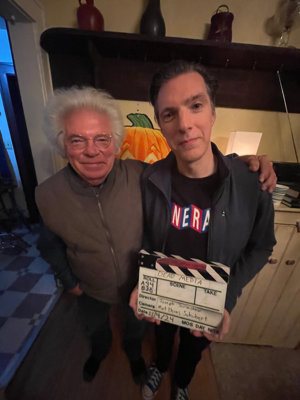 A picture of an older man and a slightly younger older man holding a slate board