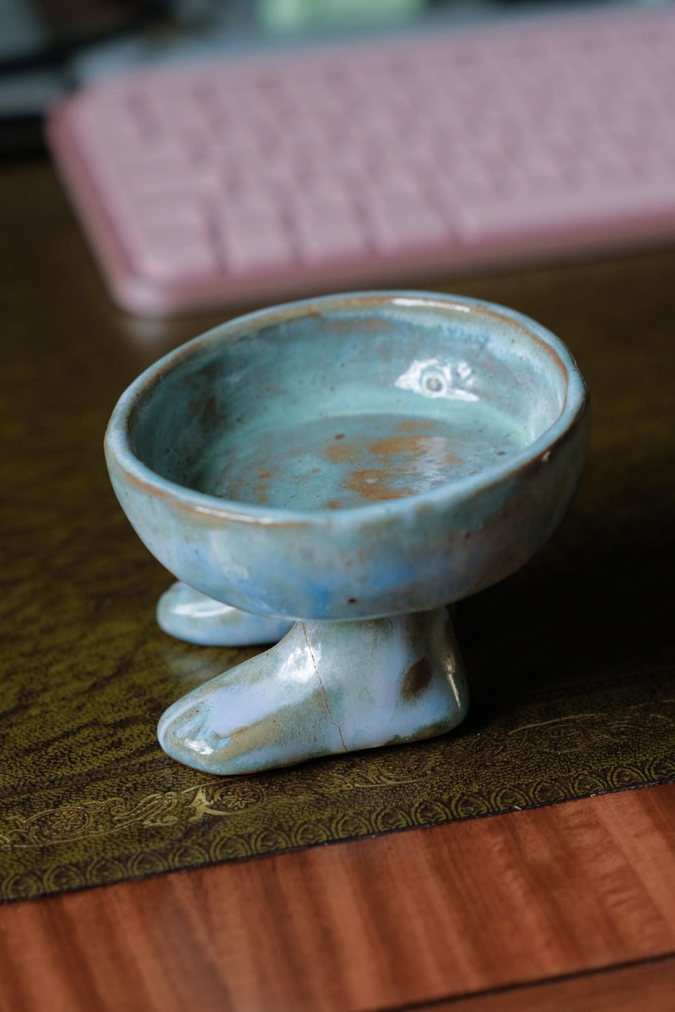 A photo of the glued-together footed bowl. A barely perceptible line runs across one of the feet, a small space between the two parts, taken up by the glue.