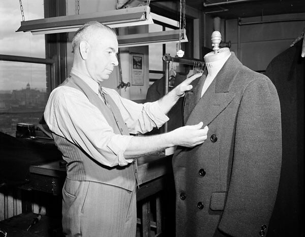 a tailor fitting a suit jacket to a mannequin