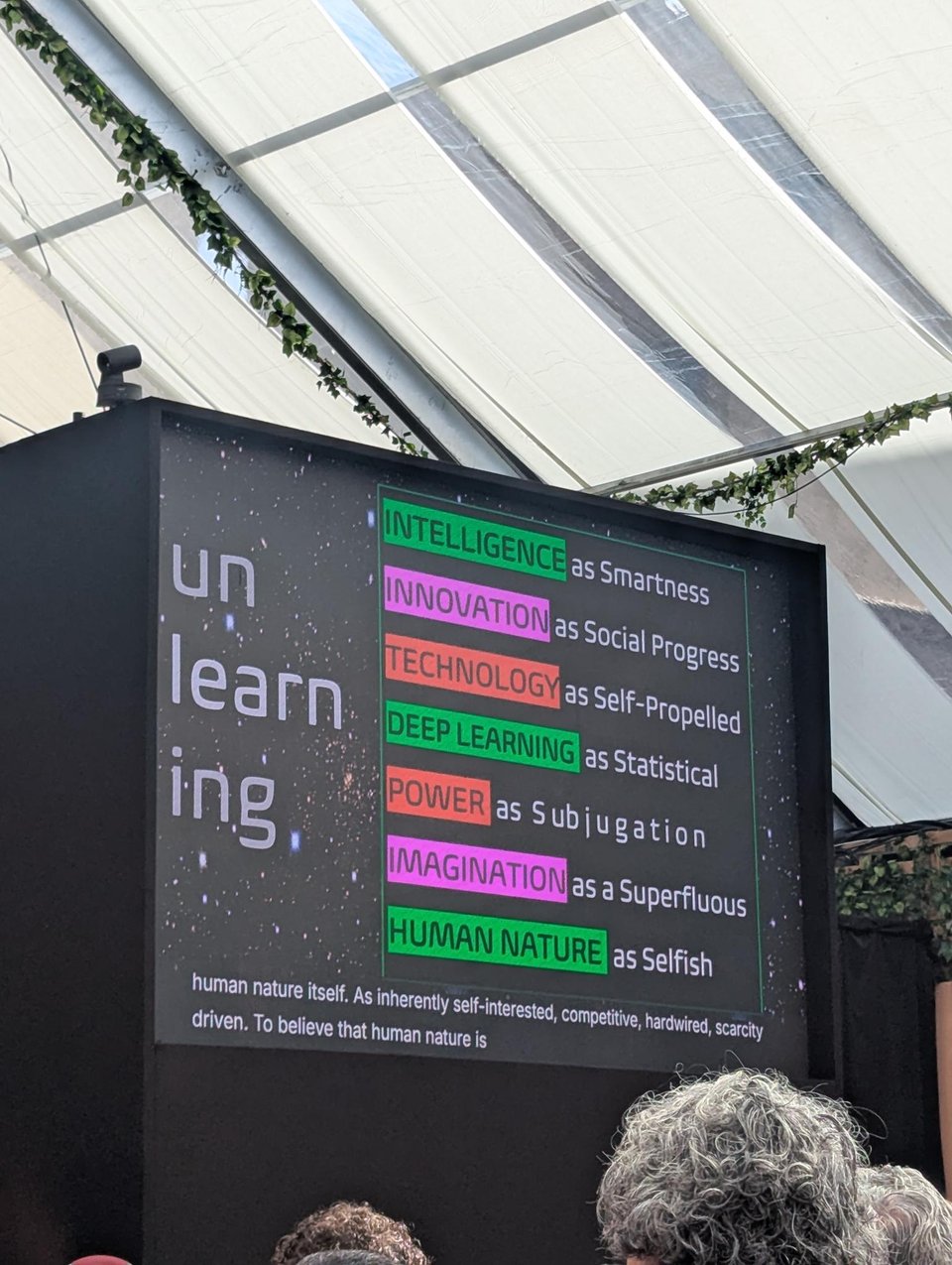 A photo of a screen. On the left it says "unlearning" against the background of stars, on the right are the following points:     intelligence as smartness      innovation as social progress (following Toni Cade Bambara: "not all speed is movement")      technology as self-propelling      deep learning as statistical      imagination as superfluous      power as subjugation      human nature as selfish