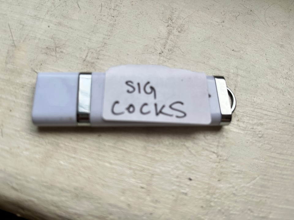 thumb drive with "SIG COCKS" written on sticker