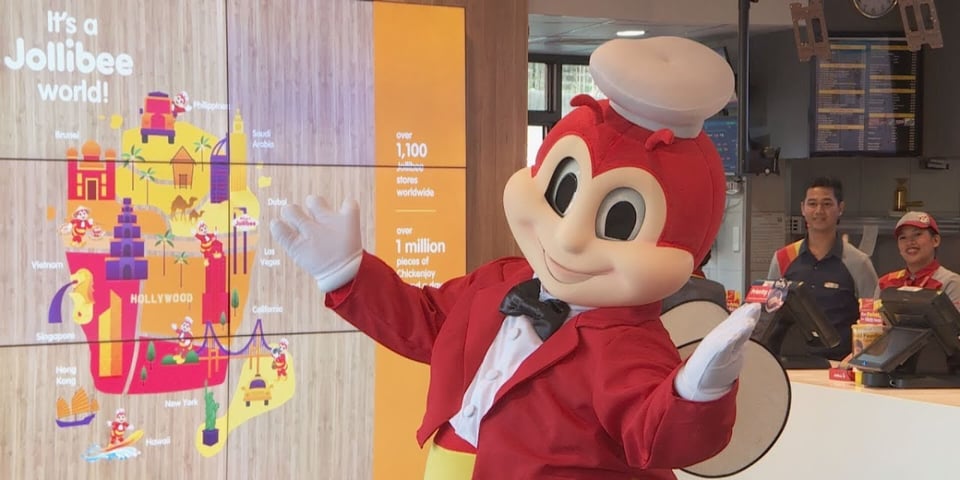 Jollibee pointing to a chart that details his fast food empire.