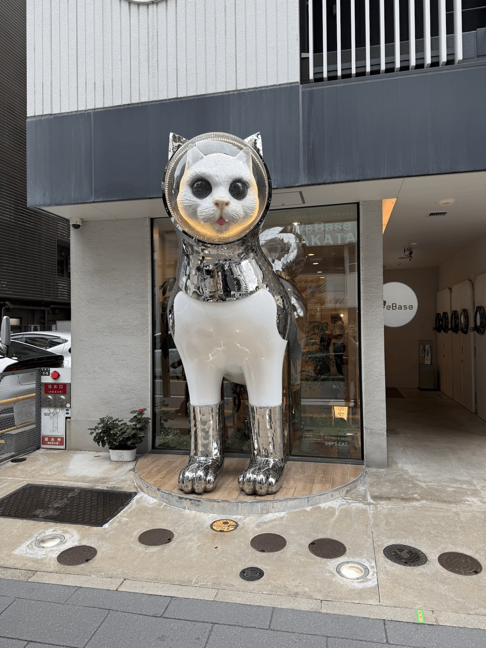 A large statue outside of a store of a white cat wearing a space suit.