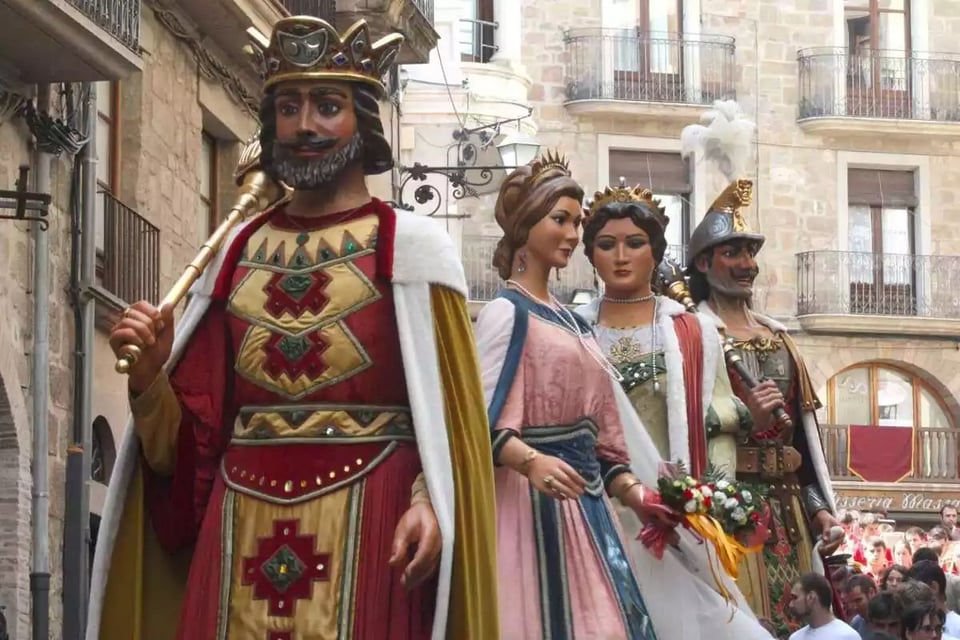 Four gigantic puppets or statues are lined up in preparation for a parade, in the Catalonia region of Spain. They depict a king, two queens, and a Roman soldier.