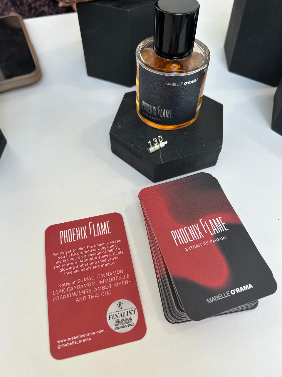 A bottle of Phoenix Flame perfume by Mabelle O'Rama alongside red and black cards with descriptions of the perfume. Image by Rowan Ambrose.