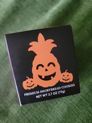 A small box from the Honolulu Cookie Company. There is artwork of jack o’lanterns including a pineapple with a jack o’lantern face.