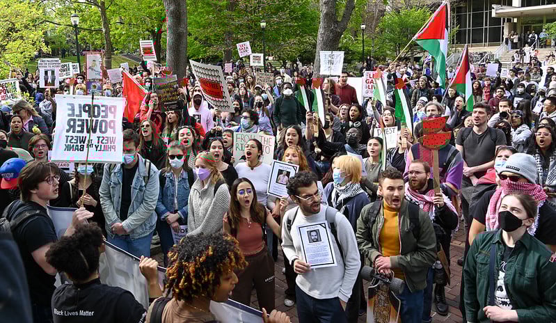 a group of students holding palestinian flags and watermelon paintings, many but not all wearing masks