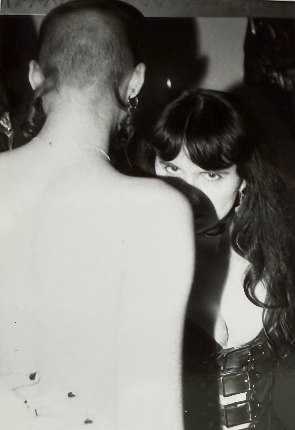 Me at 25, dressed in leather with my arm around the waist of a tall, androgynous nude person with a shaved head.