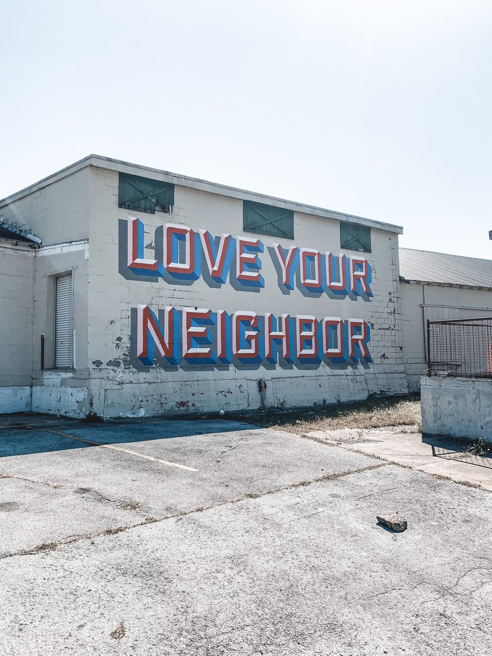 The side of a building that is painted with the words "Love your neighbor"