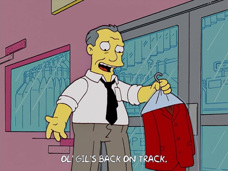 screen cap of Simpsons image of a salesman leaving a dry-cleaners, with the closed-caption text: OL' GIL'S BACK ON TRACK