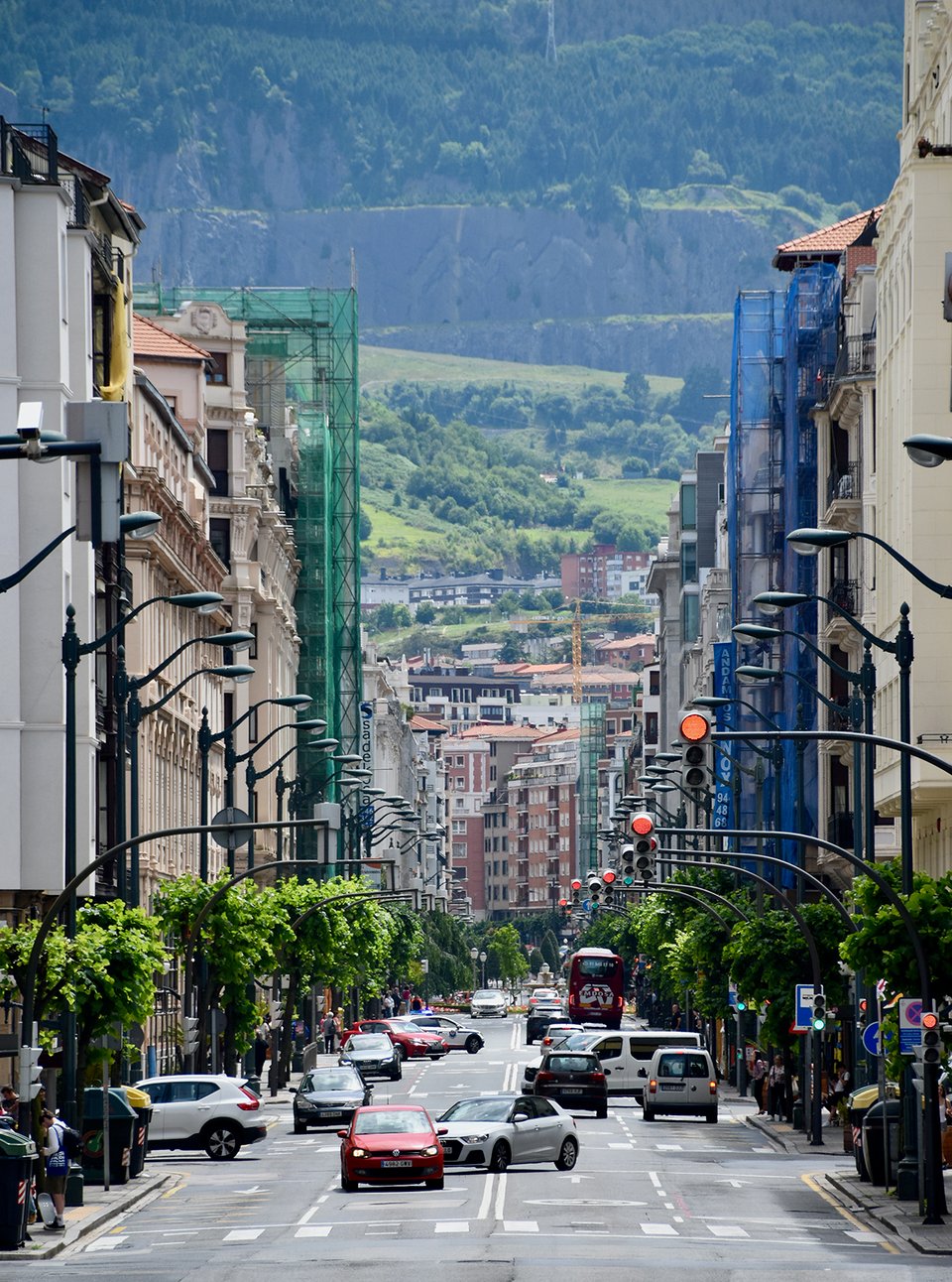 A highly zoomed photo of a city street with a mountainside in the background.