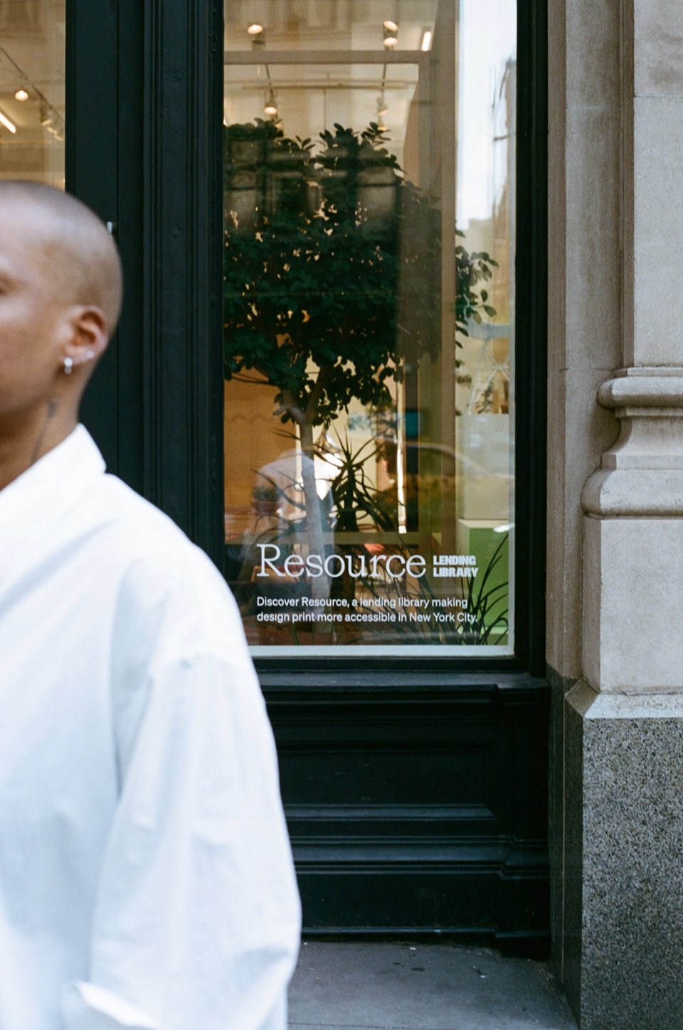 A green and glass door with vinyl text that reads Discover Resource, a lending library making design print more accessible in New York City.