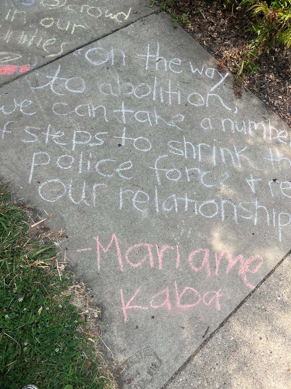 Mariame Kaba quote in chalk on the sidewalk that reads, "On the way to abolition, we can take a number of steps to shrink the police force and re[structure] our relationship[s]."