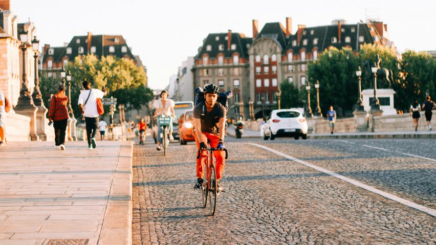 A cyclist riding down a cobblestone street on a bridge in Paris.