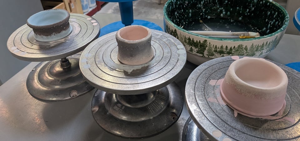 the same three small bowls from the previous picture, but now sitting on little metal stands and glazed in various colors