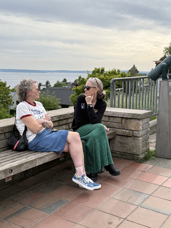 Two people sitting on a bench overlooking water near Seattle