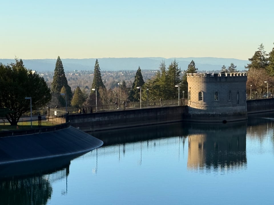 A water reservoir with a medieval-style guard tower over looking a city.