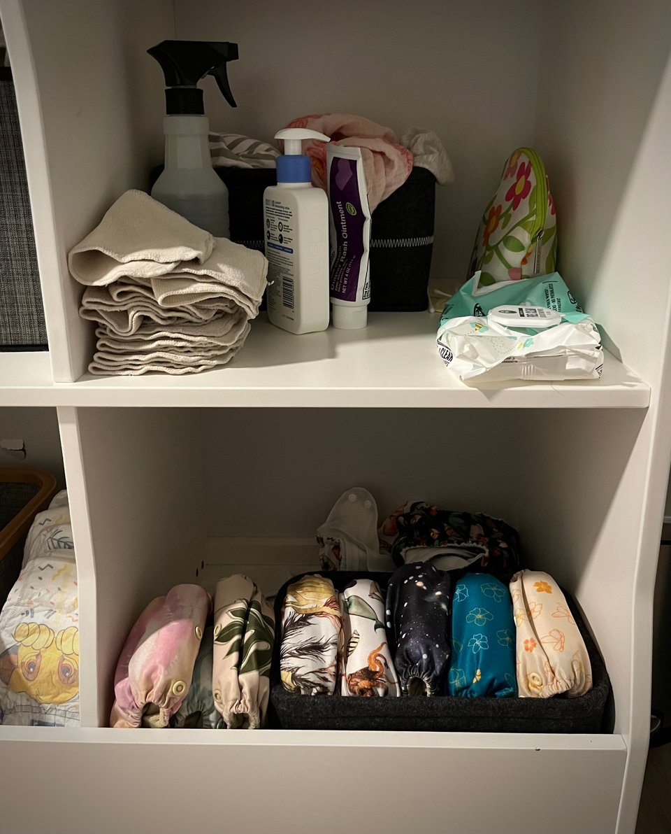 Top shelf: spray bottle and reusable wipes, but also some “real” wipes for when things get serious. Bottom shelf: nicely folded row of reusable diapers (and also some Huggies).
