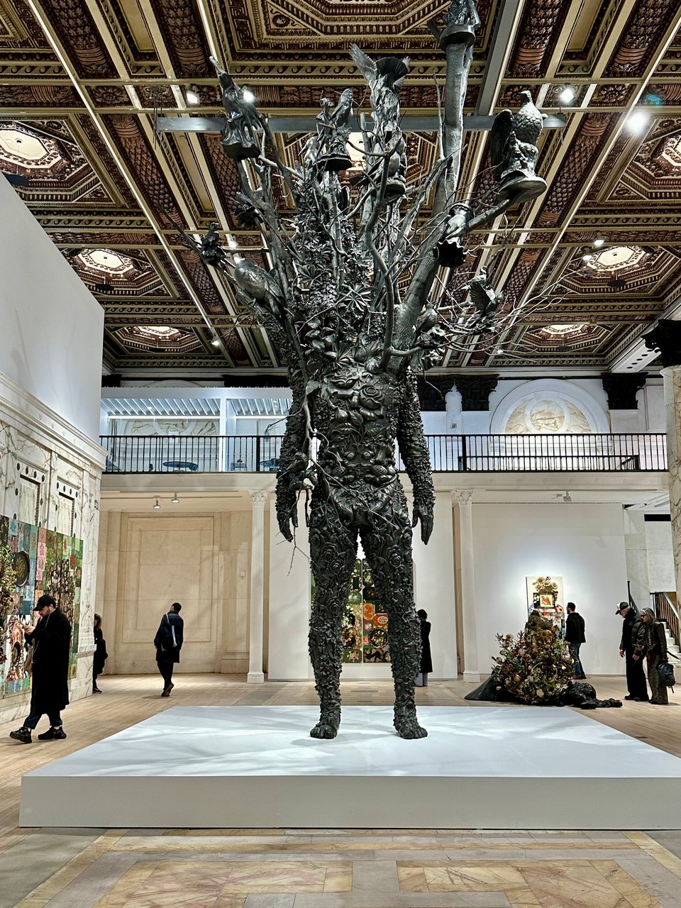 photo of 25-foot-tall dark bronze statue of a man composed of flora & fauna, with tree limbs & branches & birds in place of his head